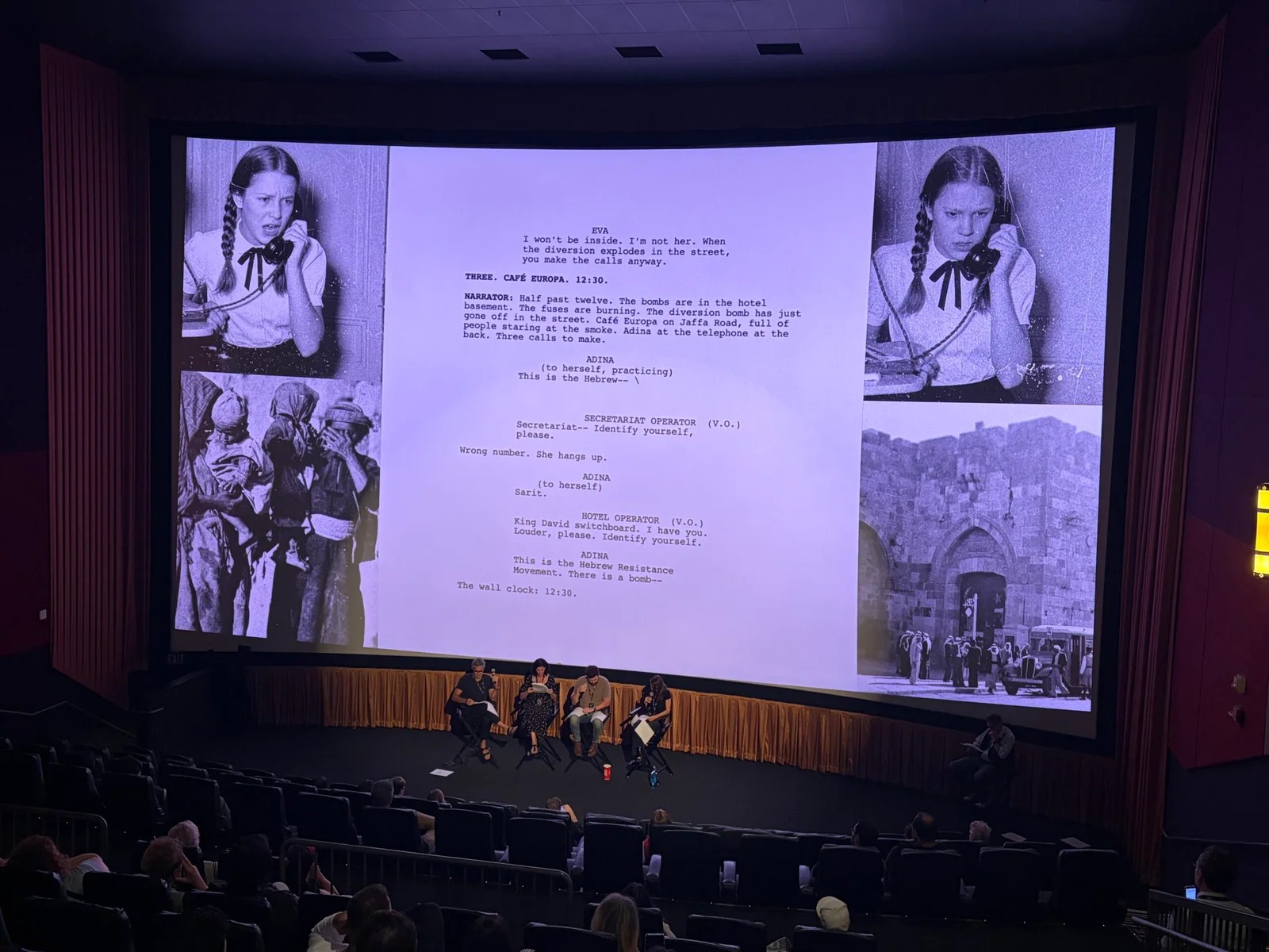 A cinema seen from the back rows: four actors seated on stage reading, with a page of the 12:37 pilot script and archive photographs projected on the screen above them.